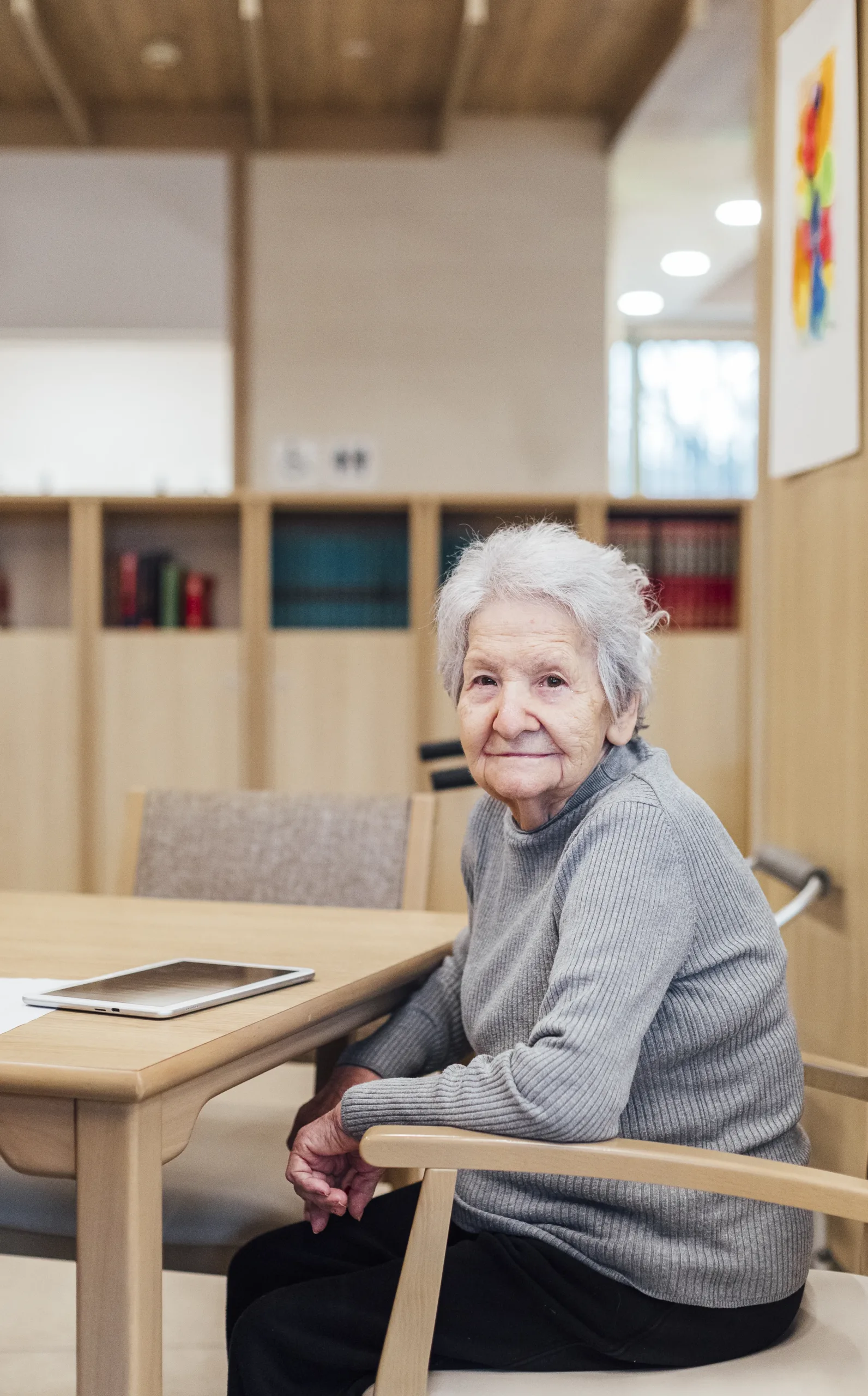 Señora mayor sentada con su tablet en la mesa Señora mayor sentada mirando en la biblioteca con su tablet en la mesa