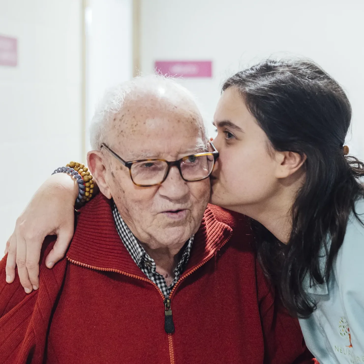 Hombre mayor con jersey rojo recibe cariño del personal de Neurocare Home